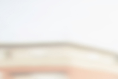 Lächelnde ältere Frau mit kurzen grauen Haaren schaut sich ein Fotoalbum an am Fenster mit Blick auf eine Stadtlandschaft.