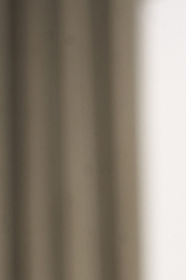 Älterer Mann in rotem Pullover hält einen Bilderrahmen und lächelt, während er ihn betrachtet. Natürliche Wohnatmosphäre.